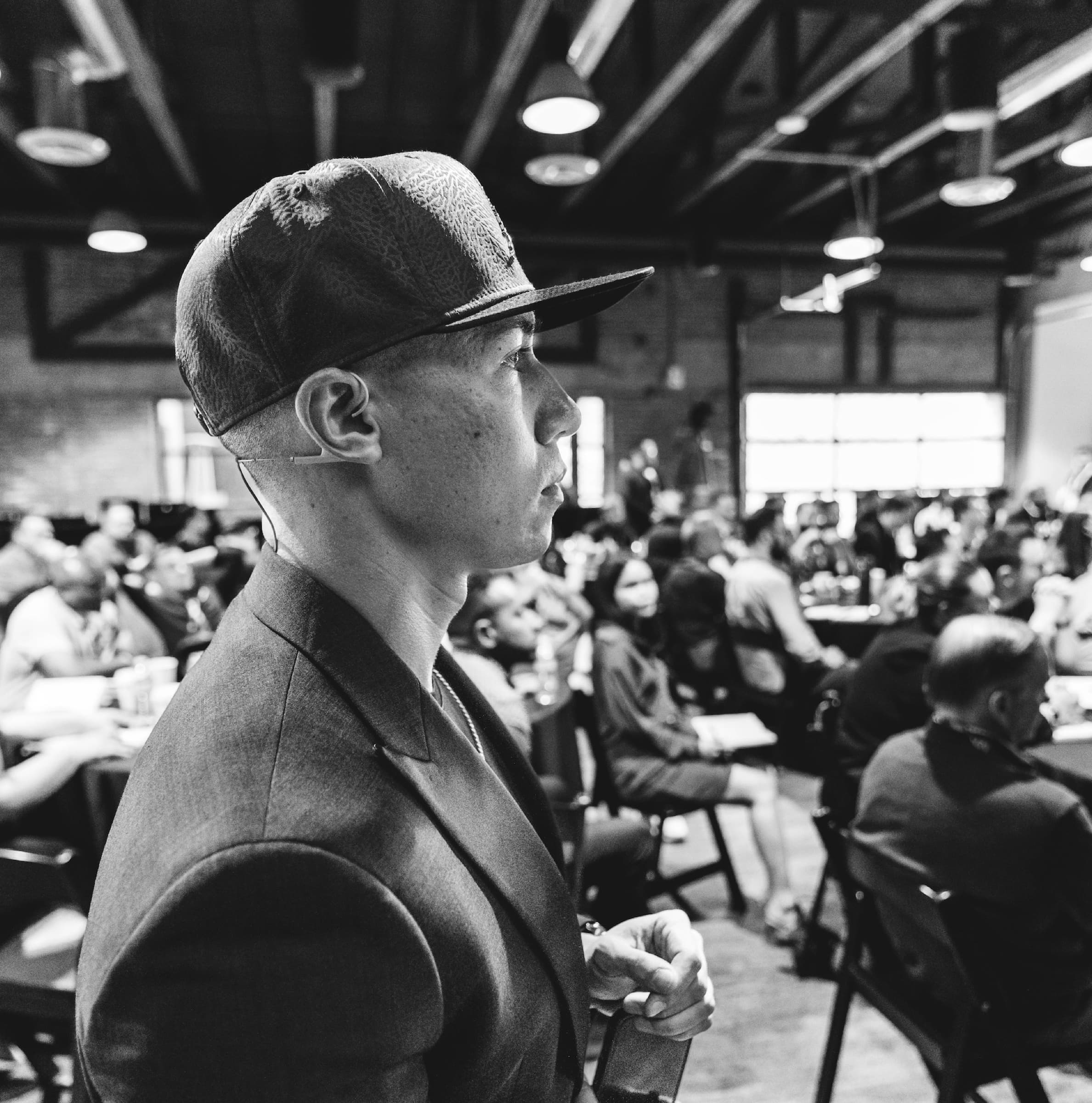 Joe Wanner in profile, watching a full room from the floor
